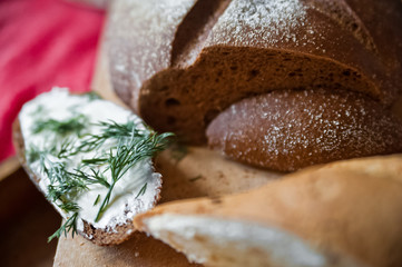 Sliced baguette and round rye black bread. Sandwich with bread, butter and dill. White loaf and rye bread close up and copy space
