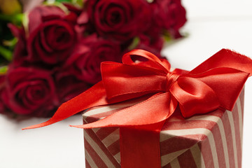 A bouquet of red roses, gift and hearts on table. Concept Women's Day or St. Valentine. Copy space