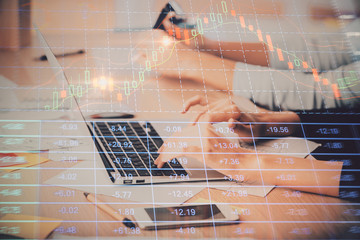 Hands typing on laptop. Business and Financial concept. Double exposure of stock market charts.