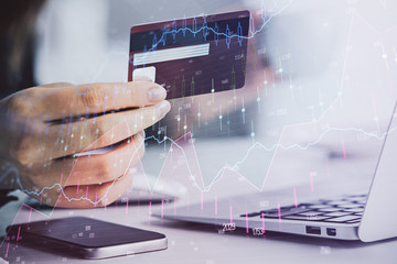 Hands typing on laptop. Business and Financial concept. Double exposure of stock market charts.