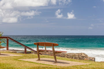 Empty park bench overlooking turquoise ocean water