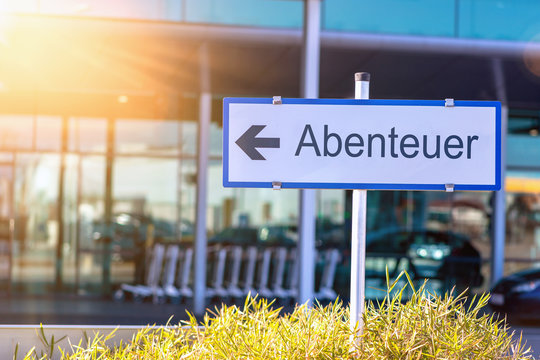 Schild vor einem Flughafen miz dem Hinweispfeil Abenteuer