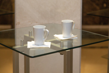 Two white cups on the glass table