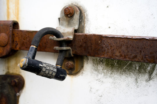 Old combination lock on a rusty gate valve on the old trailer doors