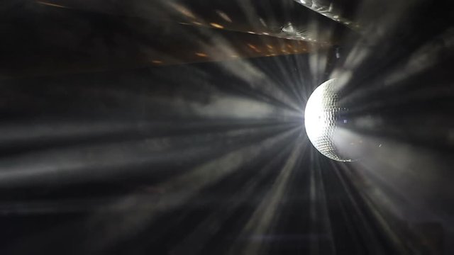 Rays of light reflecting from the disco ball, illuminate the smoke. Disco Ball Spinning seamless with Flares on Black Background.