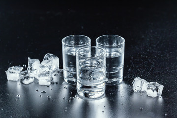 Cold vodka in shot glasses on a black background.
