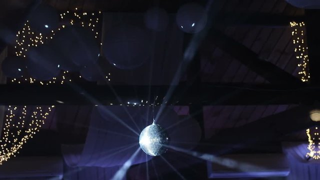 Rays of light reflecting from the disco ball, illuminate the smoke. Disco Ball Spinning seamless with Flares on Black Background.