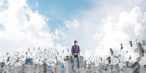 Attractive man sitting on pile of paper documents.