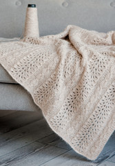 The plaid hand work and the stack of the same are lying on the couch