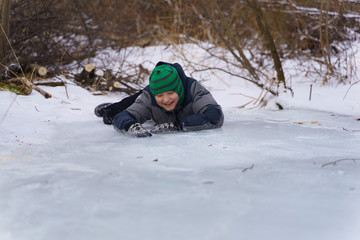Fototapeta na wymiar Happy boy lying on the ice in the afternoon in winter