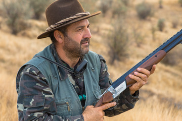 Hunter with a hat and a gun in search of prey in the steppe	