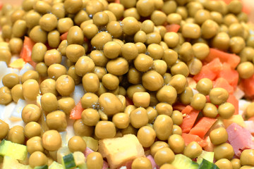Canned green peas sprinkled on top of chopped vegetables when cooking Russian salad