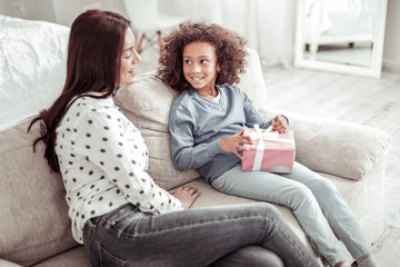 Attractive nice woman sitting on the sofa together with a girl