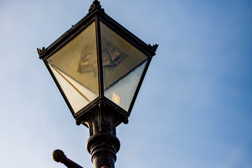 Fototapeta na wymiar Black metal Victorian style street lamp captured against a blue cloudless sky