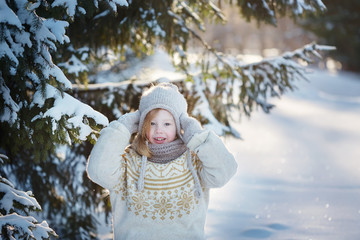 little cheerful girl in the snowy woods. Sunny winter day.