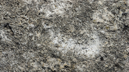 Old grey rough stone wall closeup texture background, selective focus, shallow DOF