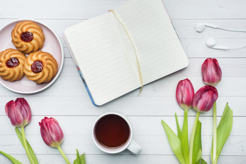 Overhead view of a bouquet of tulips and notebook and a Cup of coffee. copy space. Flat lay, top view
