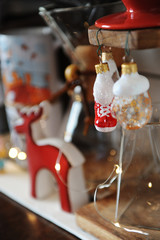 Miniature figures of skates and mittens as Christmas decorations in focus. Coffee accessories on blurred background