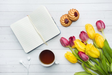 Overhead view of a bouquet of tulips and notebook and a Cup of coffee. copy space. Flat lay, top...