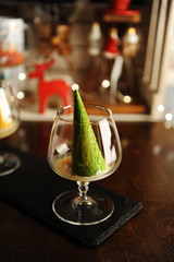Fototapeta na wymiar Food styling of Italian dessert afogato as Christmas tree with shining star. Inverted green waffle cone in cognac glass