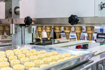 close up dough or cream and nozzle discharge of automatic biscuit or sweets making machine in production line for high technology of industrial food manufacturing