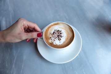 Female hand with red nails holding coffee cup