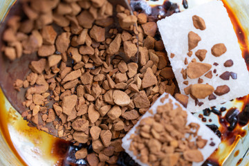 Two pieces of refined sugar and a spoon in a Cup of instant coffee.