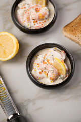 Garnelen Salat mit Lachs Kaviar,  Kräuter, Zitrone, und Vollkorn Toast Brot in schwarzer Schale auf Marmor Hintergrund