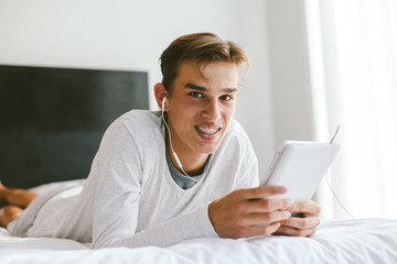 Teenager in earphones using tablet pc in room