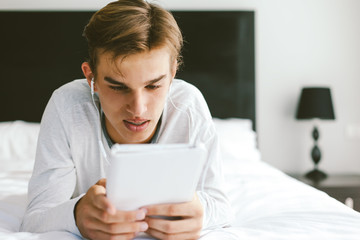 Teenager in earphones using tablet pc in room