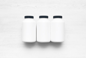 Sport nutrition jars on a white wooden table background.