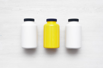 Sport nutrition jars on a white wooden table background.