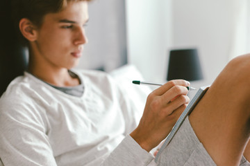 16 years old teenage boy writing school notes or doing homework