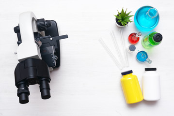 Laboratory table with a microscope and a chemical reagent liquids above. Chemistry or pharmacy...