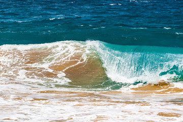 Crushing ocean wave lifting sand from the bottom