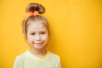 Portrait of cheerful smiling little girl on yellow background