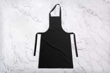 Flat lay of black apron on white marble texture. Apron on marble background. Top view