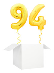 Golden number ninety four inflatable balloon with golden ribbon flying out of blank white box isolated on white background. Birthday concept.