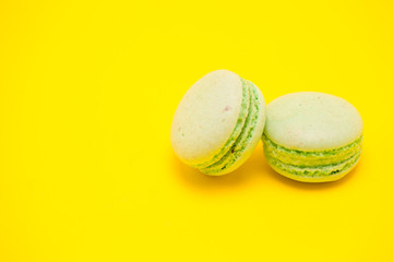 Two sweet green macaroons over yellow background