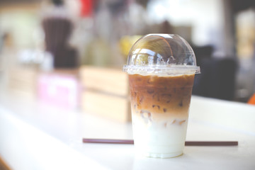 Cold coffee in plastic cup on a wooden table in cafe