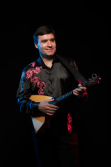 Artist musician Brunette man in a black shirt playing the guitar in blue and red scenic light on a...
