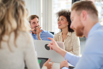 Obraz premium Small group of business people sitting at table and having meeting. Multi cultural group. Selective focus on mixed race woman.