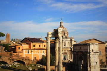 Fototapeta na wymiar Ruins of Roman Forum. Temple of Vespasian and Titus, Arch of Septimius Severus and church of Santi Luca e Martina in Rome. Italy
