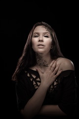portrait of young brunette girl with black tears from eyes and lace pattern on face and neck posing...