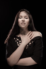 portrait of young brunette girl with black tears from eyes and lace pattern on face and neck posing...