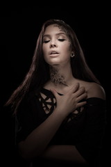 portrait of young brunette girl with black tears from eyes and lace pattern on face and neck posing...