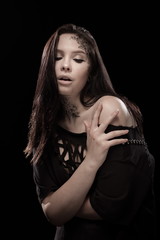 portrait of young brunette girl with black tears from eyes and lace pattern on face and neck posing...