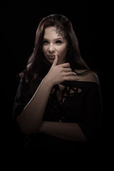 portrait of young brunette girl with black tears from eyes and lace pattern on face and neck posing...