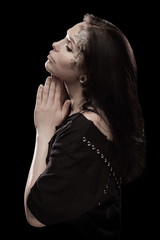 portrait of young brunette girl with black tears from eyes and lace pattern on face and neck posing...