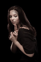portrait of young brunette girl with black tears from eyes and lace pattern on face and neck posing...